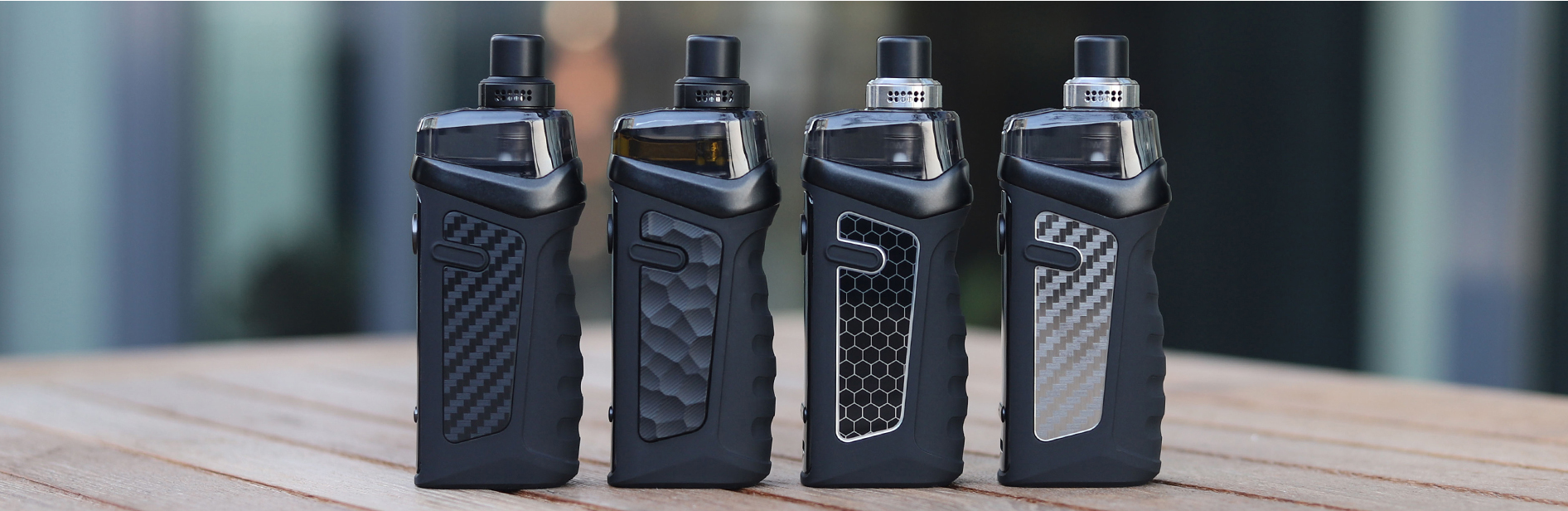 Four Vandy Vape pod devices sitting on a surface outside.