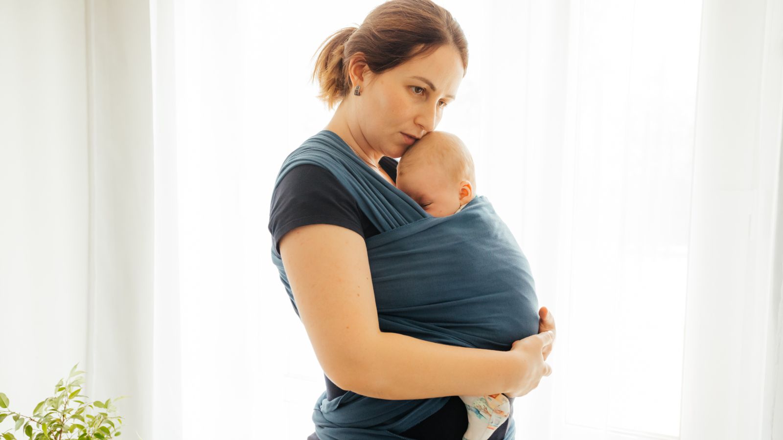 Une maman qui porte son nouveau né en écharpe.