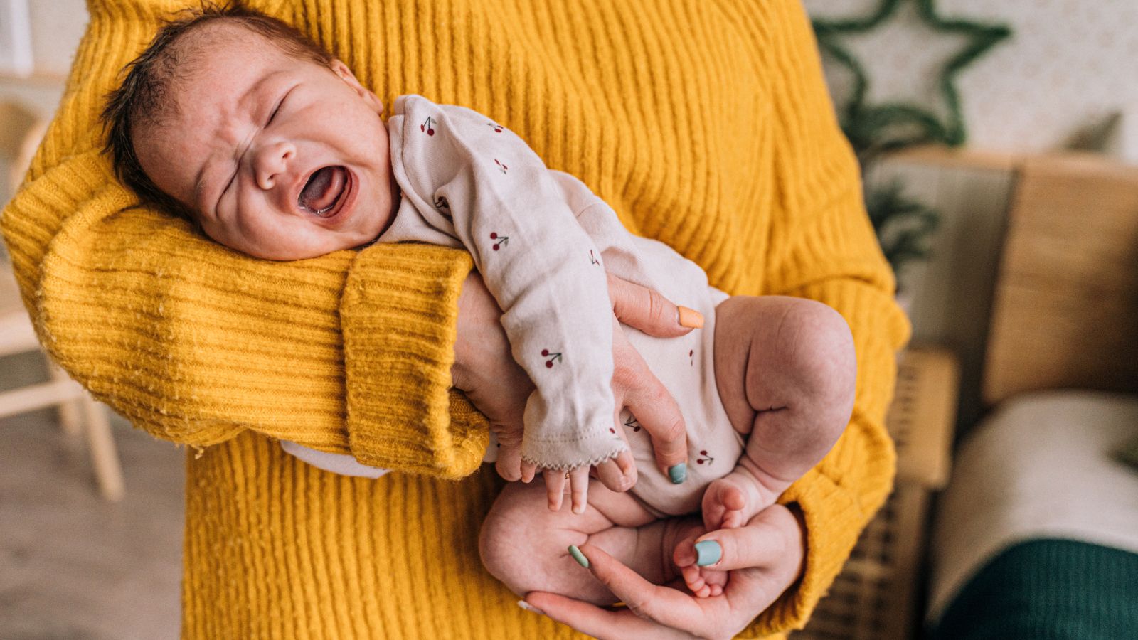 Un bébé qui pleure porté le ventre sur le bras de maman pour soulager les coliques.
