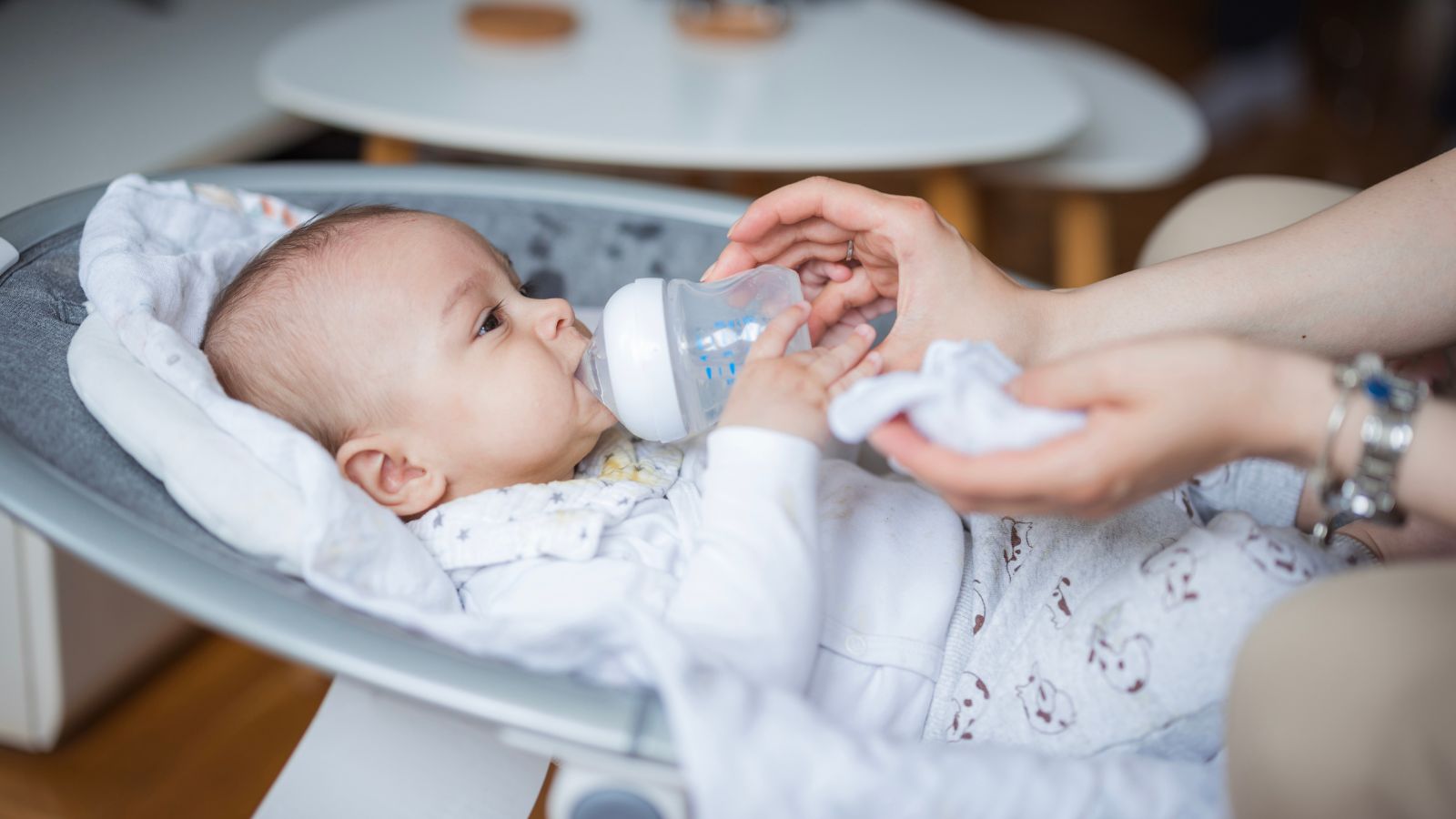maman donnant le biberon à bébé dans un transat