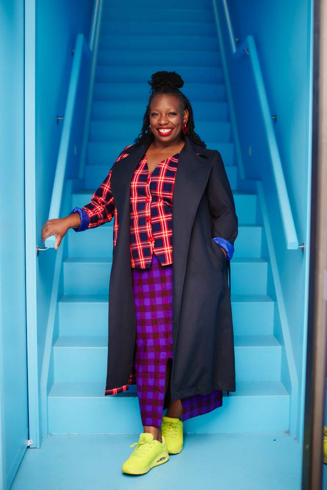 Women standing in front of blue stairs wearing Tuka Trench coat and Mpito Vest