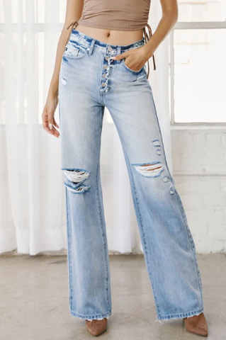 Photo of model wearing high-rise, light wash jeans with straight legs, including distressing near the knees. 