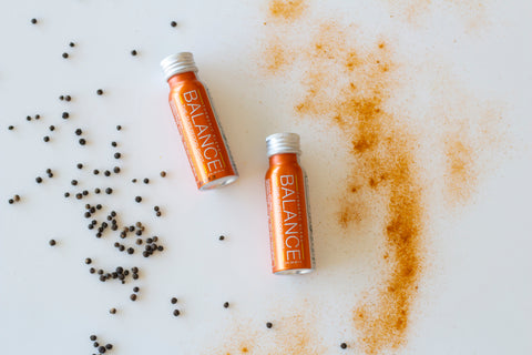 Black pepper fruit, powdered turmeric and Balance the Superfood Shot Turmeric Blend on a table