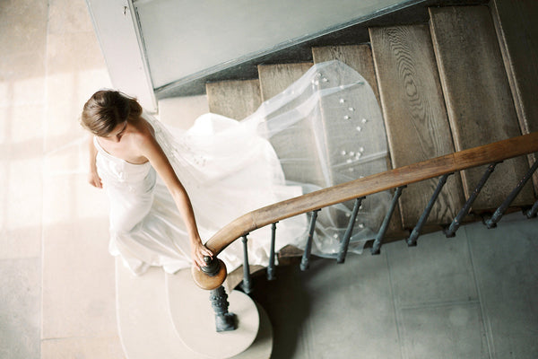 Bride walking down stair wearing a long floral wedding veil