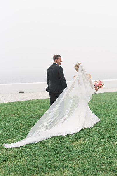 Bride and groom walking together, bride wearing a long cathedral veil