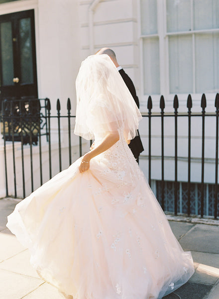 Bride and groom walking, bride is wearing a three tier elbow length veil