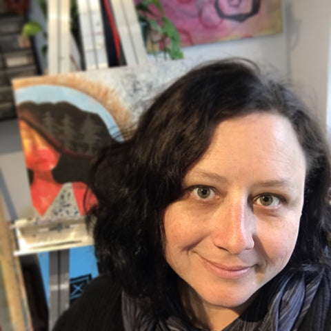 image of smiling white woman with dark, wavy hair.  behind her is an easel with a colorful painting on it.