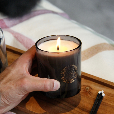 lit black glass candle on a wooden tray