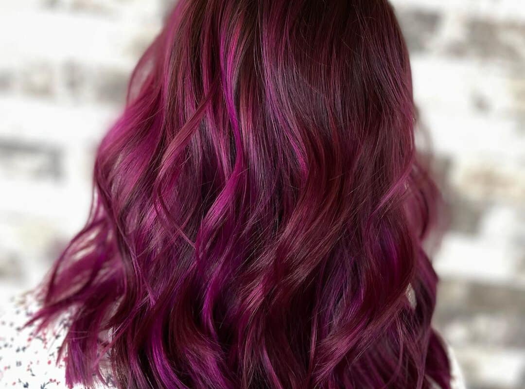 Dark pink highlights on brown curly hair