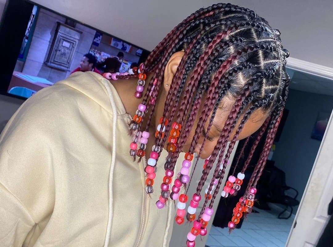 girl with black and dark brown knotless braids with colored beads