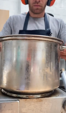 Jack's placing a large pot on the stove to melt the candle wax in preparation for the candle head, used to model Mosevic's handmade denim sunglasses