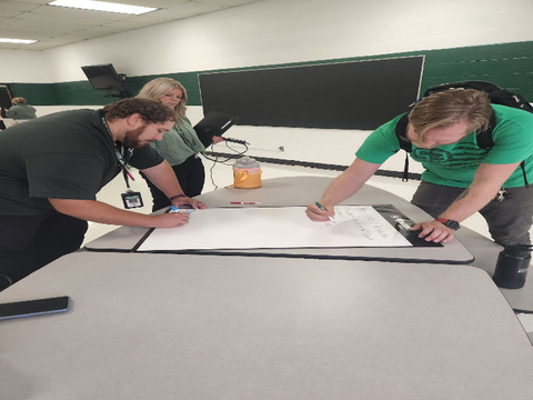 two teachers writing down in the same Flipchart