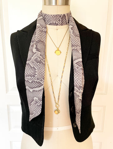 Grey snakeskin print chiffon skinny scarf layered with necklaces worn with a vest.