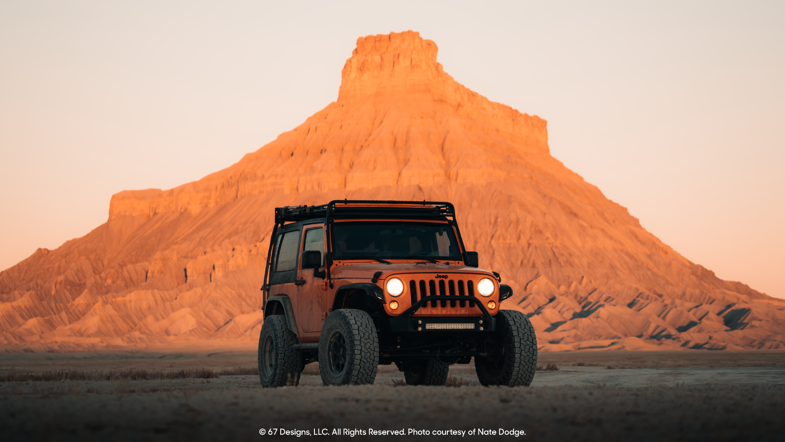 Jeep in front of a rock formation at sunset. 