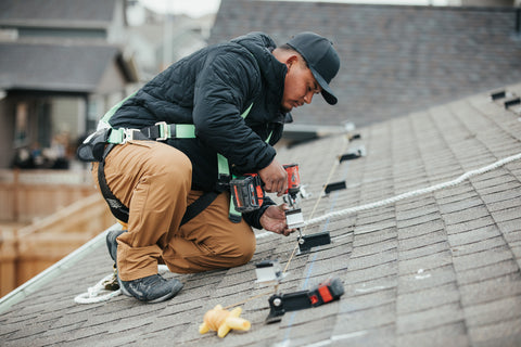 A trade professional completes a solar panel install on a roof