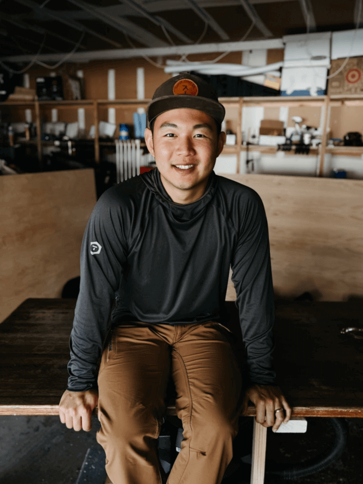 Moses Cho sits on table in a Truewerk B1 Sun Tee Long Sleeve and T2 WerkPants