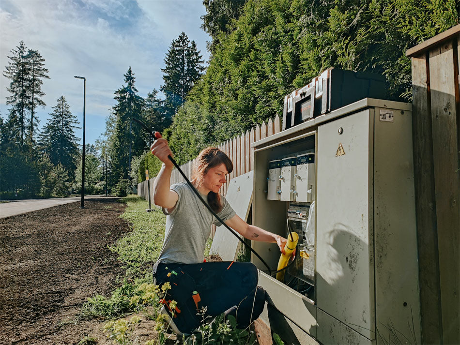 An electrician works on an electrical box outdoors.