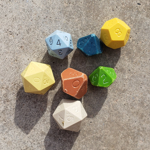A photo of an old set of DnD Dice, which are solid colored and heavily dented and difficult to read