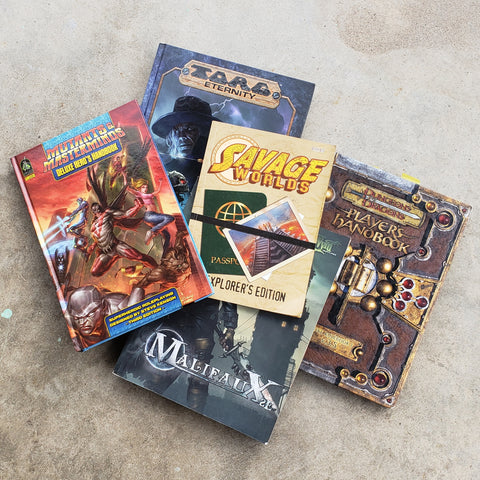 A photograph of several tabletop roleplaying games, including Savage Worlds, Mutants and Masterminds, Malifeaux, DnD 3e, and TORG