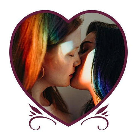 An image from the Pasion de las Pasiones book showing two women kissing. One has black hair and the other has rainbow hair. They are framed by a heart