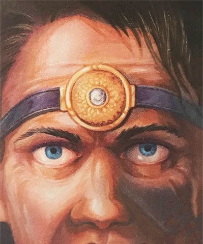 An illustration of a man's upper face and head. He has short hair and blue eyes, and has a medallion on a circlet around his forehead. The medallion is circular, with a small white stone in the middle, connected to a purple band. 
