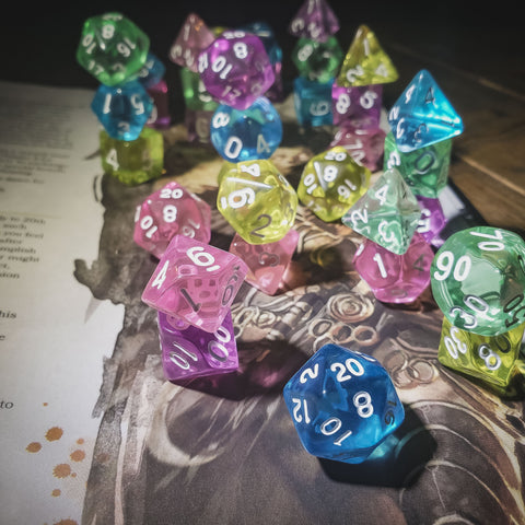 Image Description: A photograph of several sets of different colored dice on top of a dungeons and dragons book. The dice are brightly colored and mostly transparent. End description. 