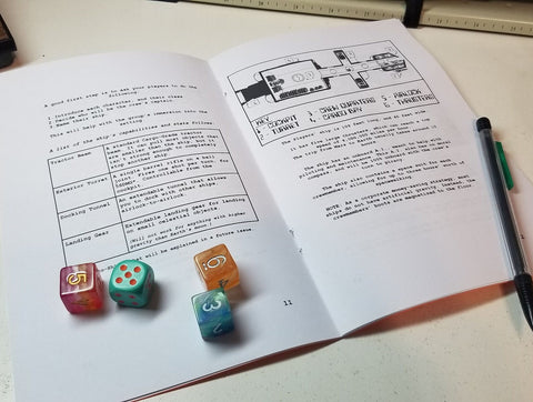 A photo of the Moxie book open, with black text on white pages. On the open pages are several colorful d6s