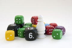 A photo of many differently colored d6 dice, with a small white pawn, against a white background