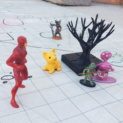 A photo of several dungeons and dragons miniatures on a battle map. The miniatures are set between several children's toys and a small plastic tree. The toys are an eraser shaped like a dog, a small figurine of the Cheshire Cat from Alice in Wonderland, and a slightly larger figurine of the superhero Daredevil from Marvel Comics