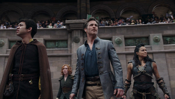 A screenshot from the Dungeons and Dragons movie trailer. It shows several people in fantasy clothes walking close to each other while looking outward. One wears metal armor, one a blue jacket, and one leather armor. 