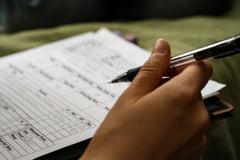 A photo of a hand holding a pen above a character sheet for a tabletop roleplaying game