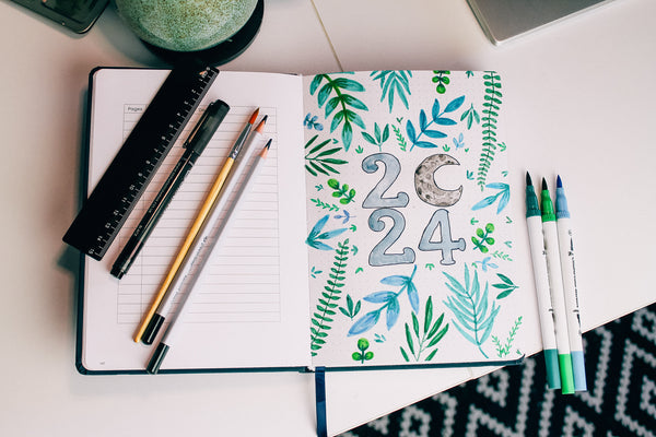 bullet journal 2024 front page spread showing a beautiful drawing of botanical leaves and a moon
