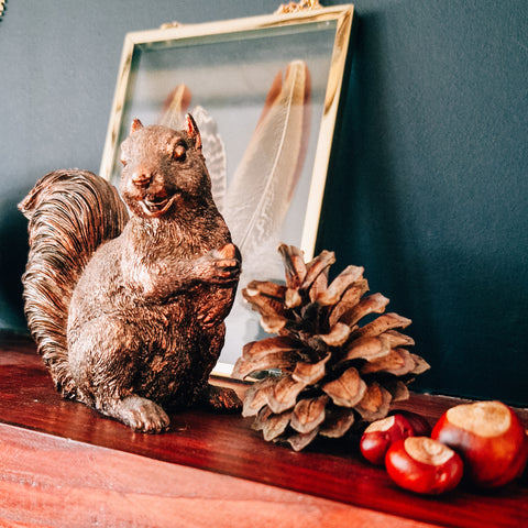 copper squirrel figurine with pinecone and conkers on a mantelpiece