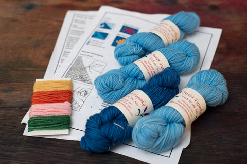 Contents of Fish in the Sea sock knitting kit: 4 mini skeins of blue yarn, printed pattern and small amounts of 5 bright colours