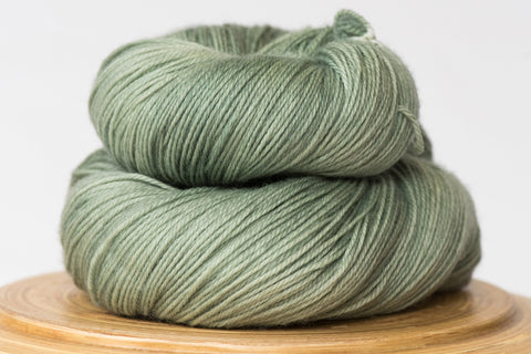 Hand-dyed superwash merino sock yarn in Cardamom, a muted sage green colour