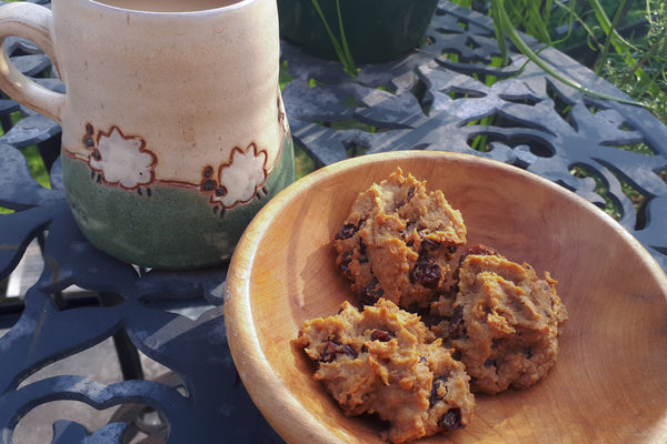 Wooden bowl with three chickpea cookies next to mug of tea