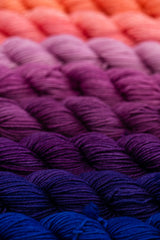 Row of purple gradient yarn skeins all lined up from dark to light