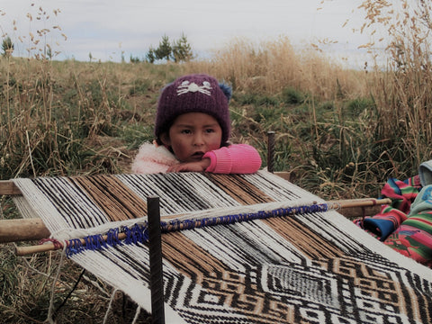 Pallay alpaca throw pillow on the loom with little girl