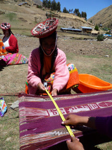 Virgina measures her weaving, as it dries, with a measuring tape donated by the LATA Foundation.