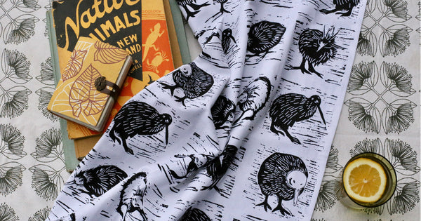 A white tea towel with images of black and white kiwi birds.
