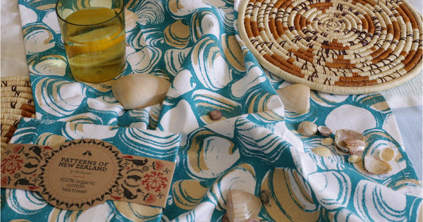 A blue and tan coloured tea towel with shells on it.