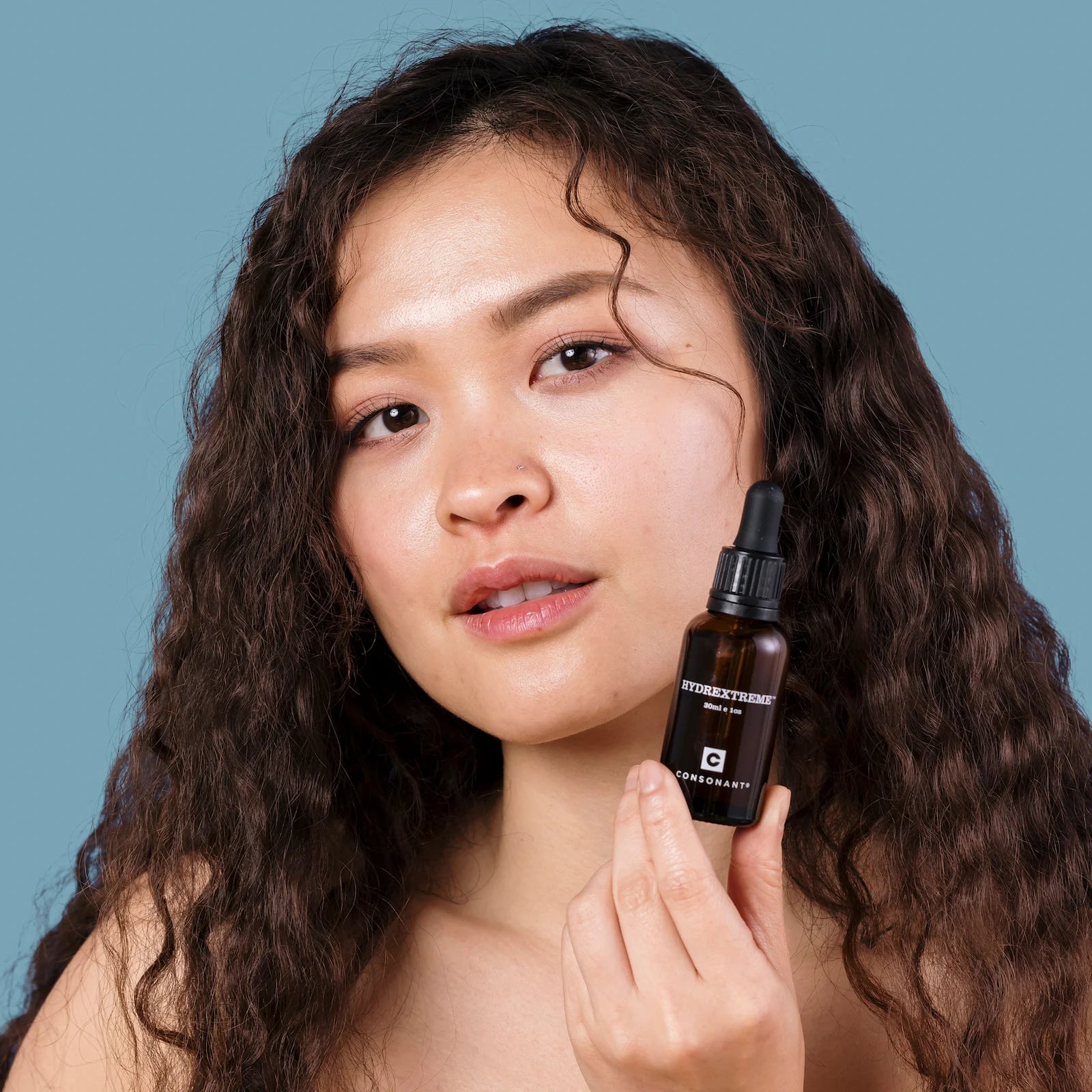 Woman holding all natural, nontoxic facial oil to her face