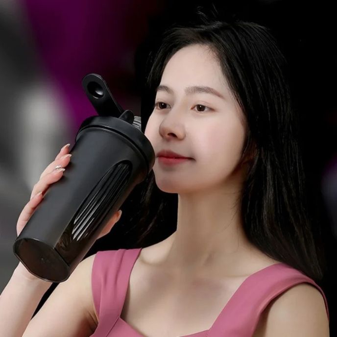 Femme en robe rose buvant dans un shaker noir