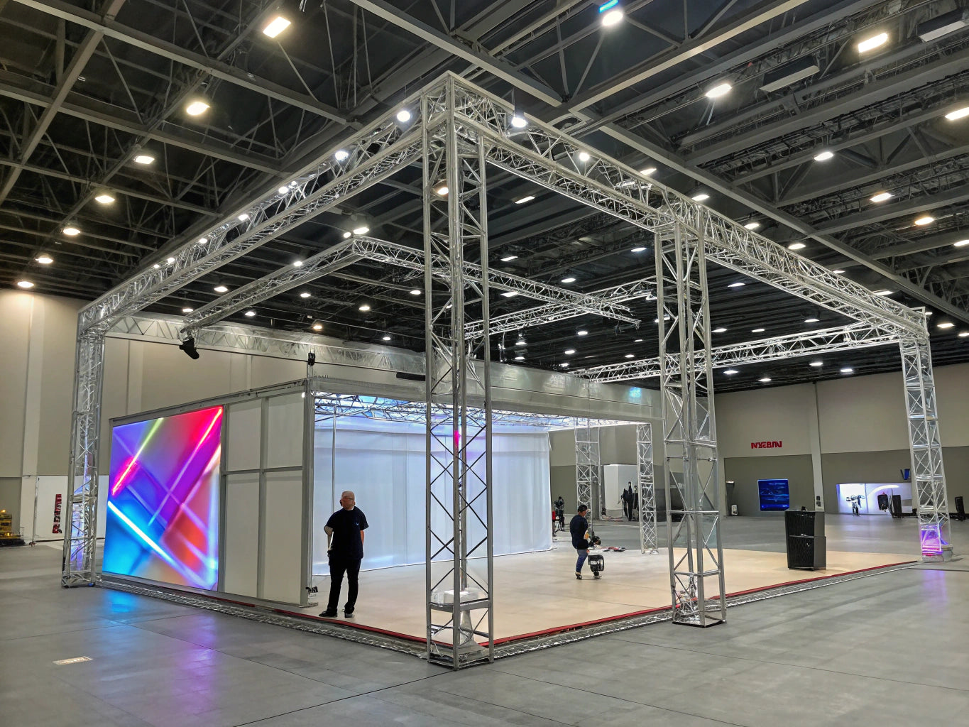 Modular truss framework in expo hall with LED lighting, data overlays, and geometric design.
