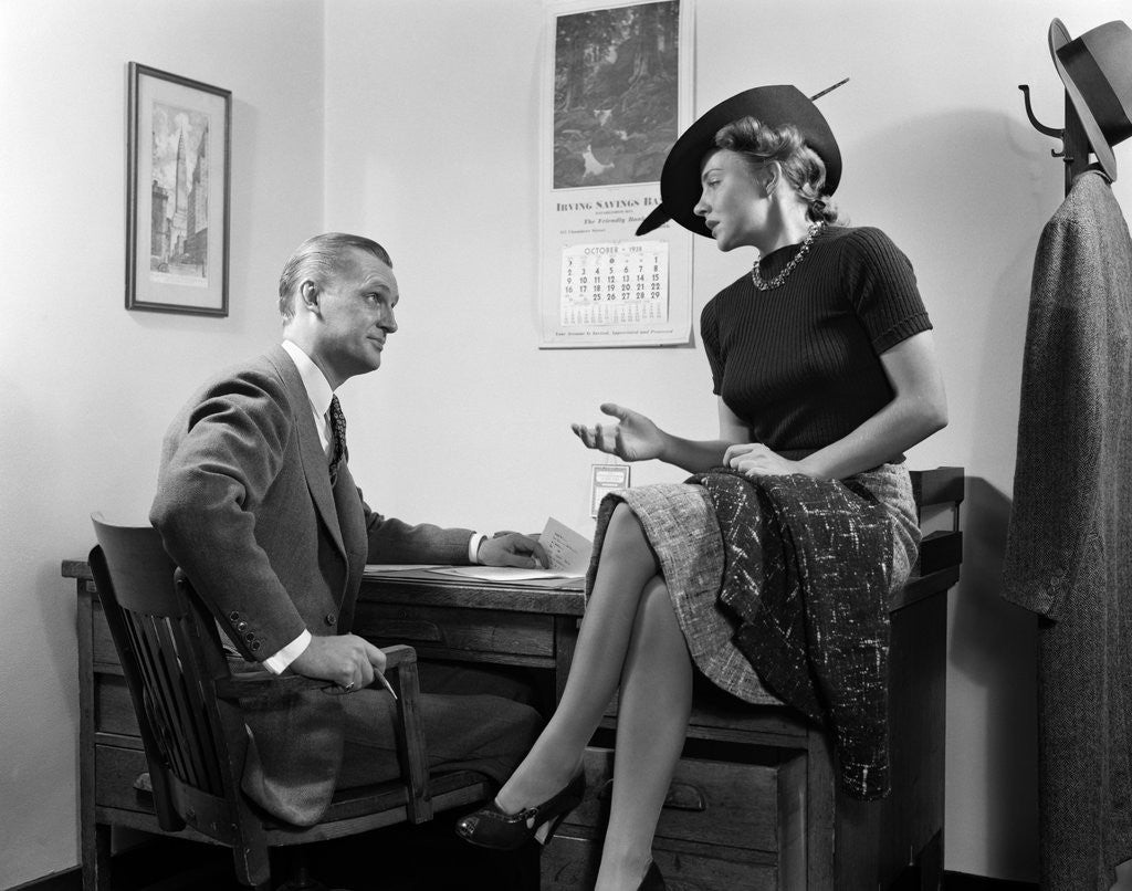 1940s Woman Sitting On Desk Hat Skirt Hand Gesture Talking Flirting ...