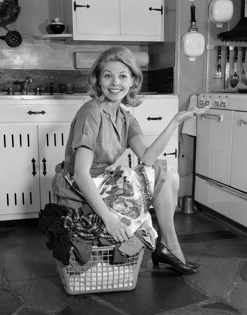 1960s smiling housewife sitting on full laundry basket posters & pri picture