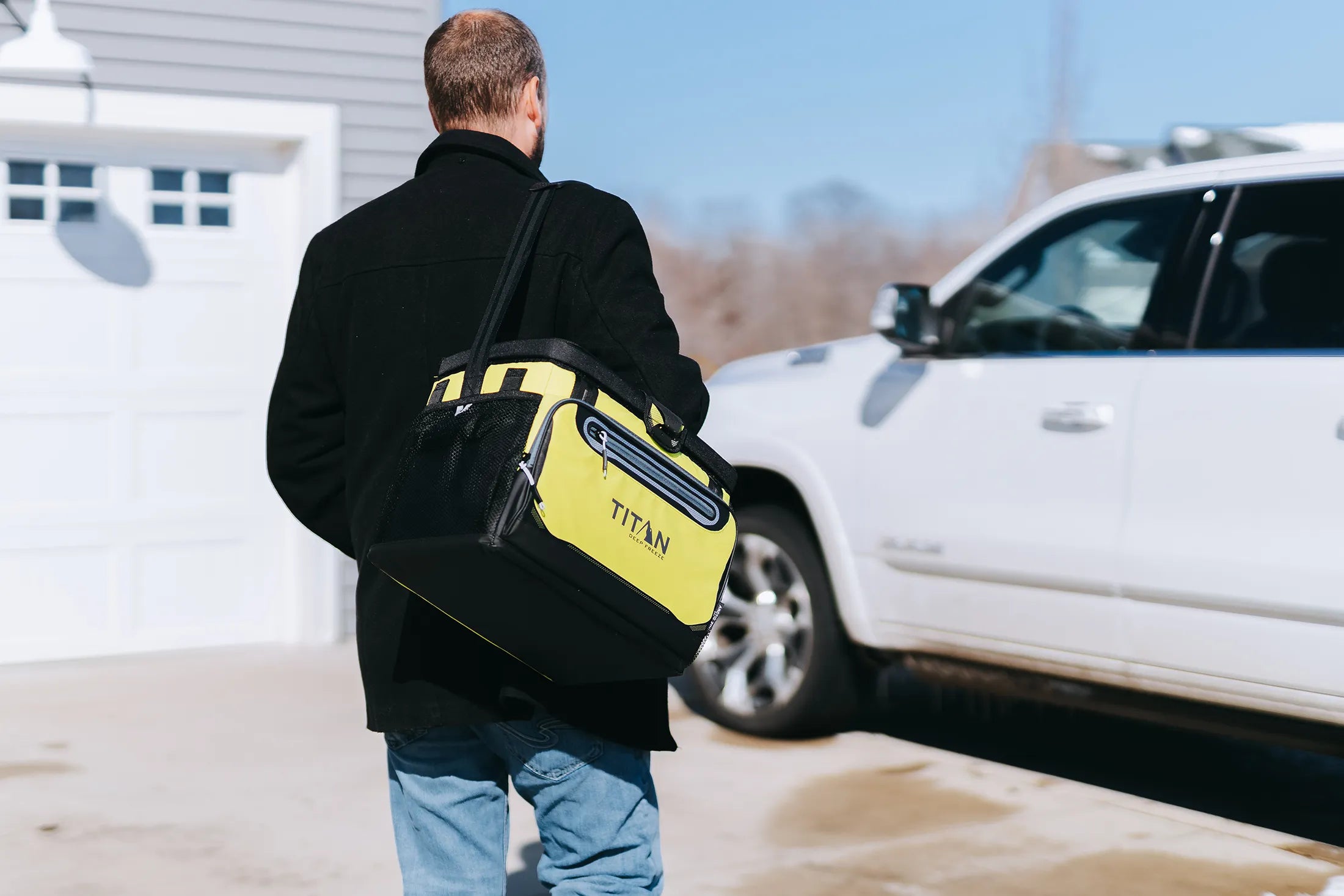 Guy carrying a Titan Cooler while walking to his car