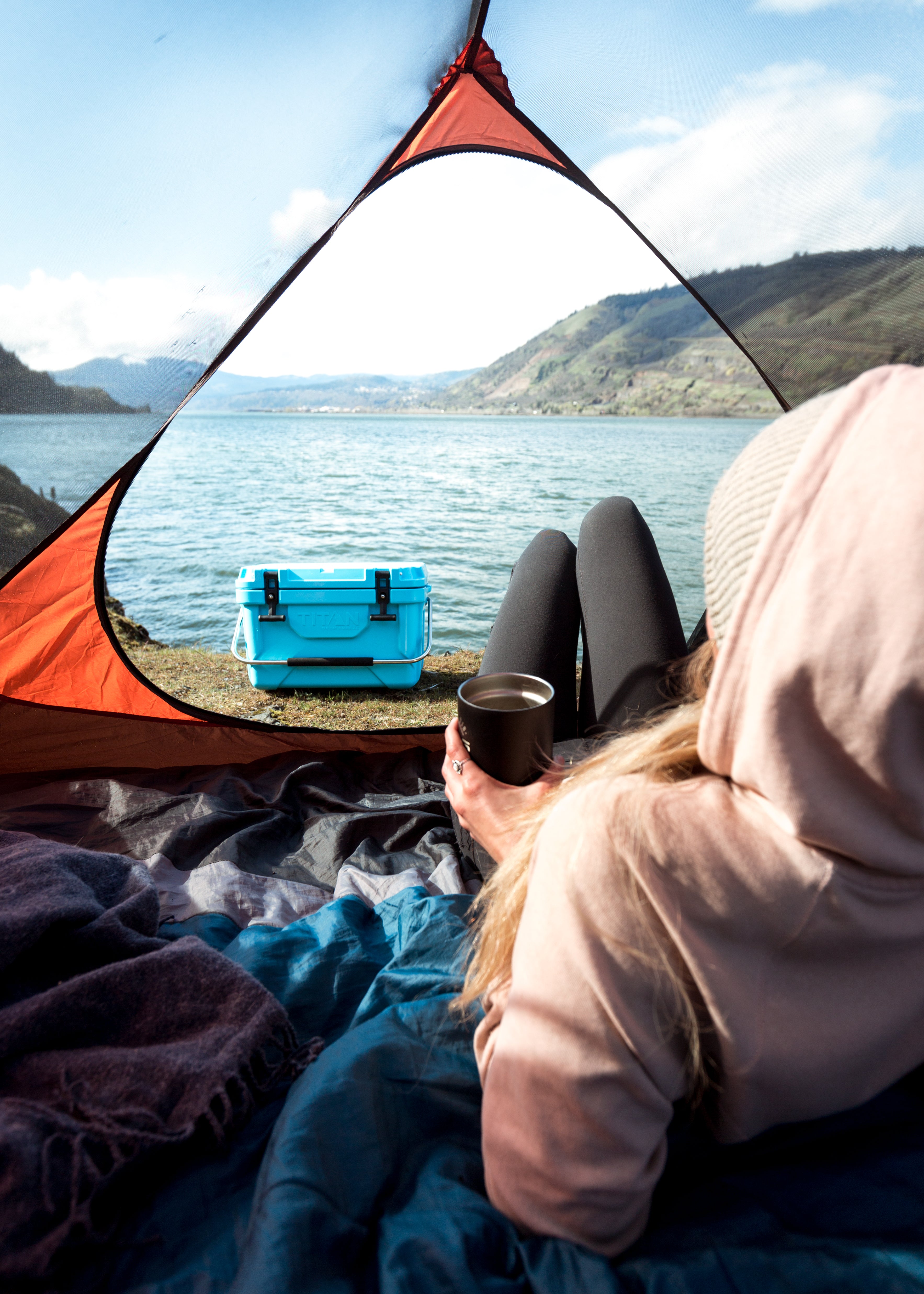 Camping with Arctic Zone - carrying the cooler past the tent - chilling in the tent with a drink overlooking a lake - Best coolers for camping 