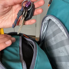 Person putting key in backpack cooler.