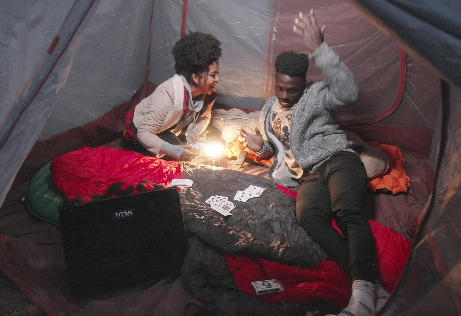 Two people playing cards in a tent while camping